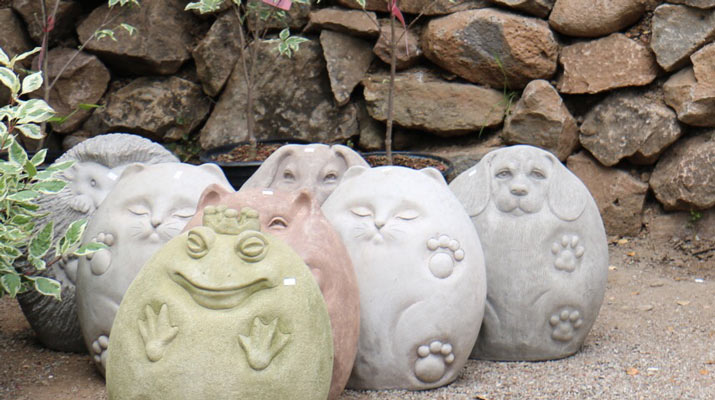 garden decorations in pale colors in front of a stone wall