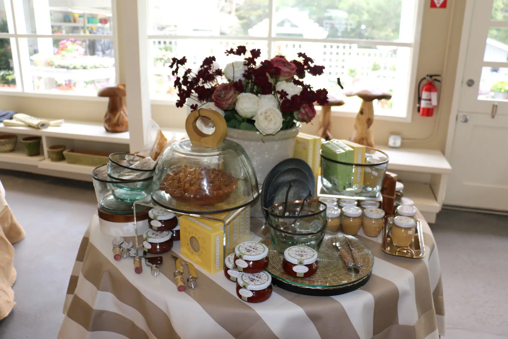A home design store table wtih flowers and dishes and food items and a striped tablecloth